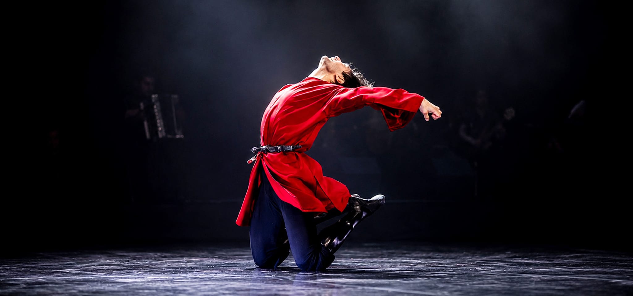 Dancer in a red chokha arched backwards on one knee
