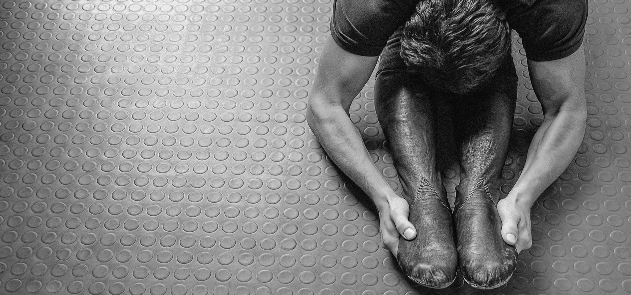 Black and white close-up of a dancer lacing his boots